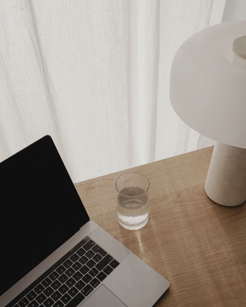 Laptop und Glas Wasser auf einem Schreibtisch – Arbeitsumfeld bei stameedia Coaching.